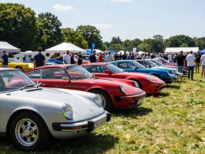 Outdoor automotive event showcasing various classic and exotic cars with attendees