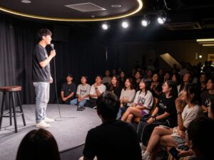 Stand-up comedian performing in front of an enthusiastic audience at a comedy club.