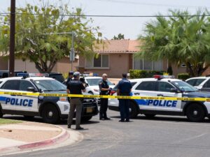 A police scene in West Phoenix showing multiple police vehicles and evidence markers.