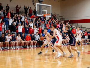 High school basketball players competing during a lively game with enthusiastic fans.