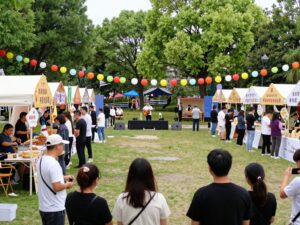 Community gathering at The Joy Lush Club anniversary celebration with food and music.