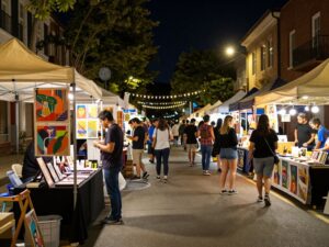 Crowd enjoying the First Friday Artwalk in downtown Phoenix with art displays and food stalls.