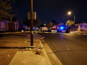 Nighttime view of a damaged light pole on a street in Peoria, Arizona, with police tape indicating an ongoing investigation into a fatal accident.